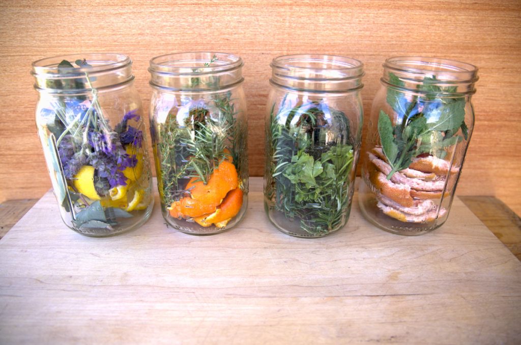 jars filled with fruit peels and herbs for cleaning vinegar infusion