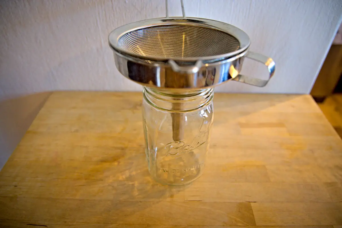 using a funnel and strainer to strain homemade chicken broth