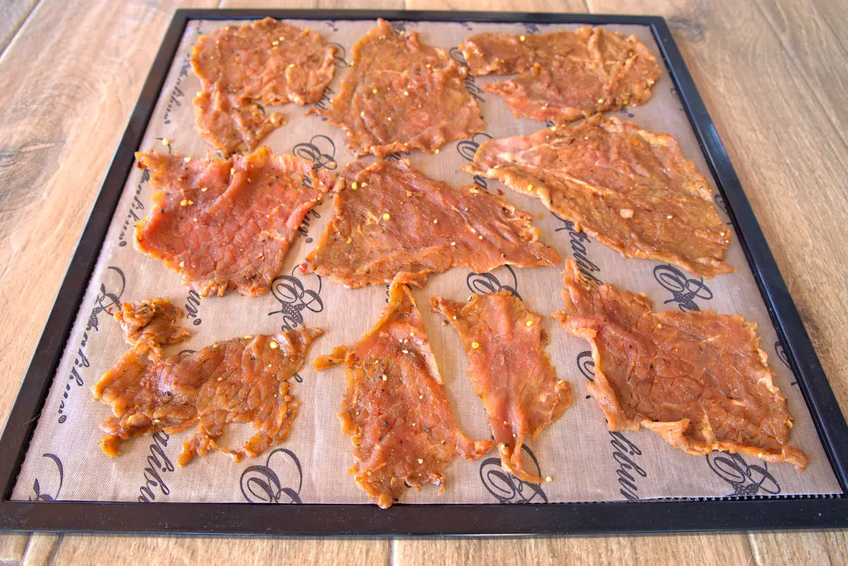raw beef slices on dehydrator tray to make beef jerky