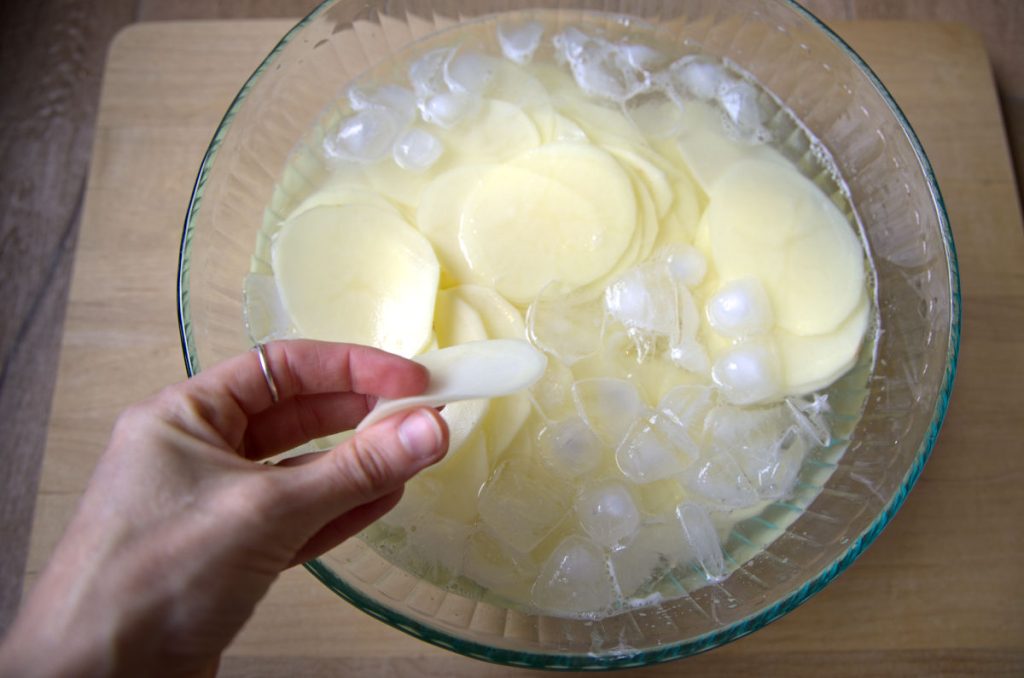 soaking sliced potatoes in an ice bath for homemade potato chips